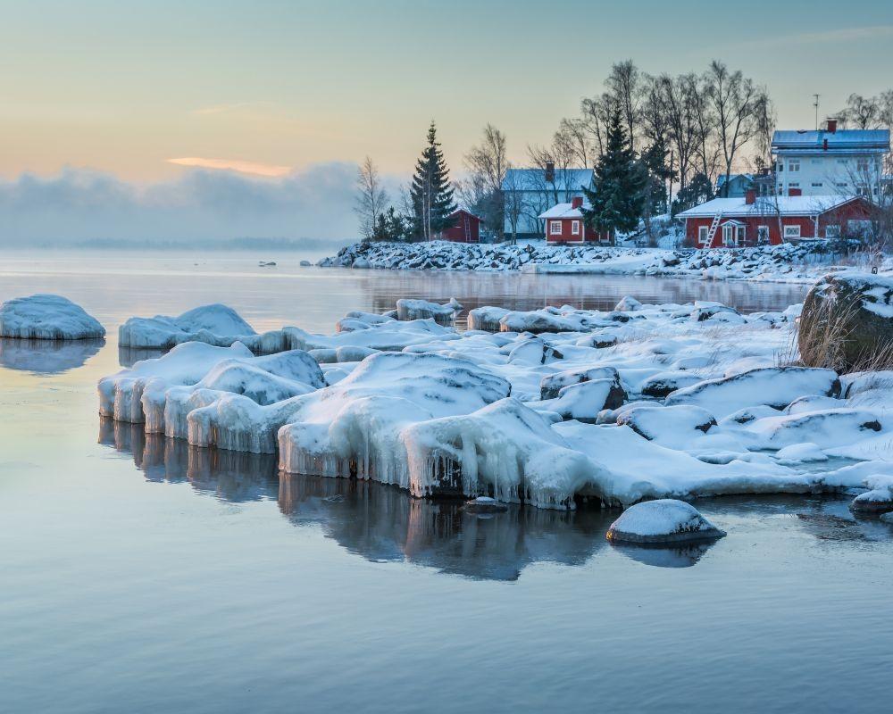 Tranquillo paesaggio invernale con lago e casette rosse